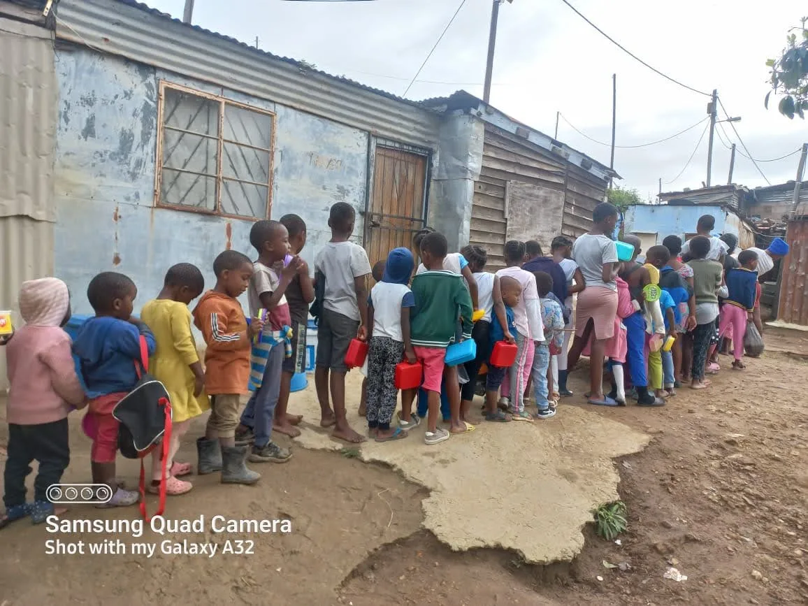 Children queuing with cups during an OTEGA Foundation school feeding programme